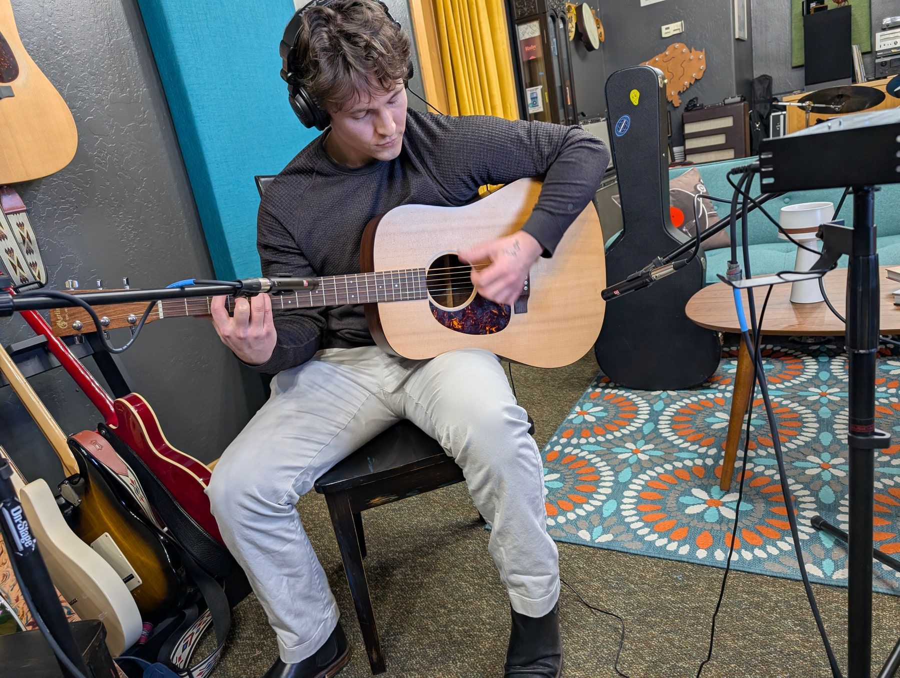 An acoustic guitarist recording with two microphones in the live room