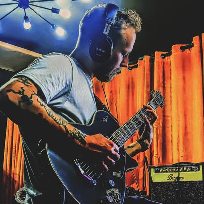 A guitarist recording an electric guitar part in the live room