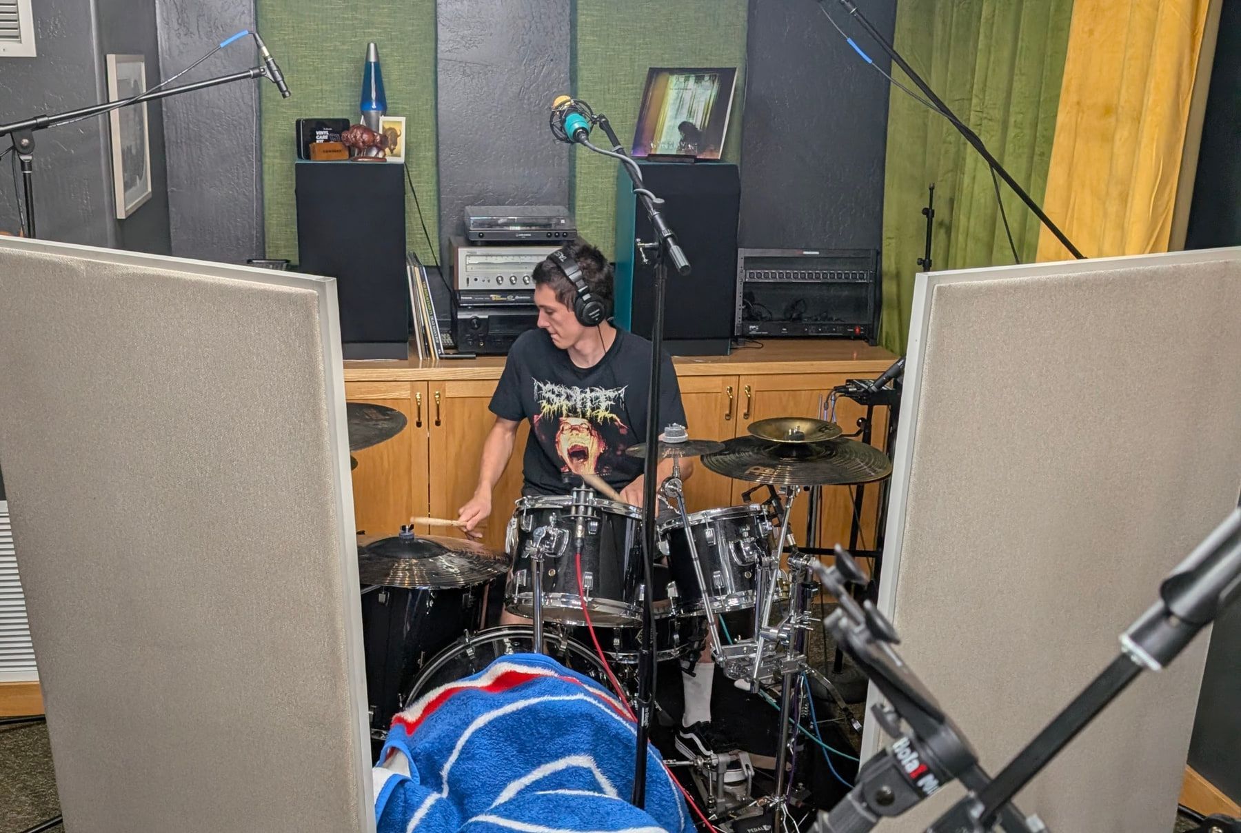 A drummer recording a live kit between acoustic panels