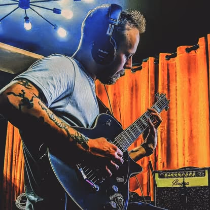 A guitarist recording an electric guitar part in the live room