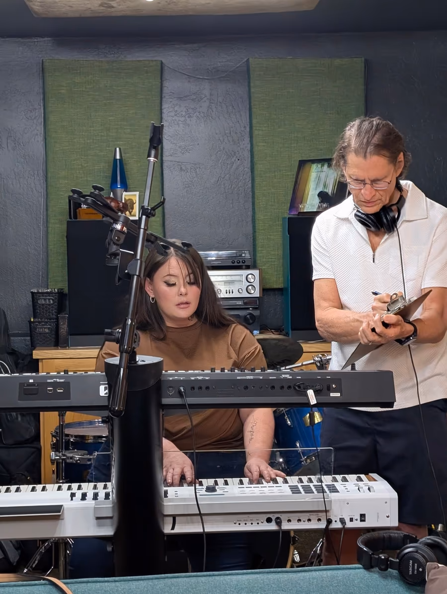 A keyboard player and producer preparing a part in the live room